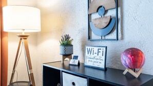 A desk with a lamp, a Wi-Fi sign, a decorative wall piece, and a small plant. - The Cozy Chickasha | Fiber | Extra Parking | W/D (Chickasha)