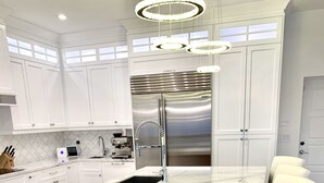 Una cocina moderna con armarios blancos, una isla de mármol, electrodomésticos de acero inoxidable y detalles de madera.