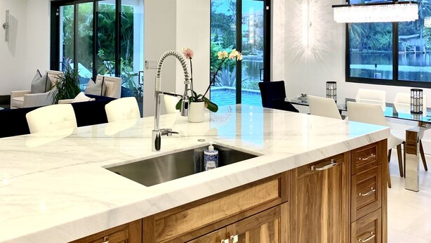 Una cocina moderna con una isla grande, iluminación colgante y amplios ventanales con vistas al exterior.