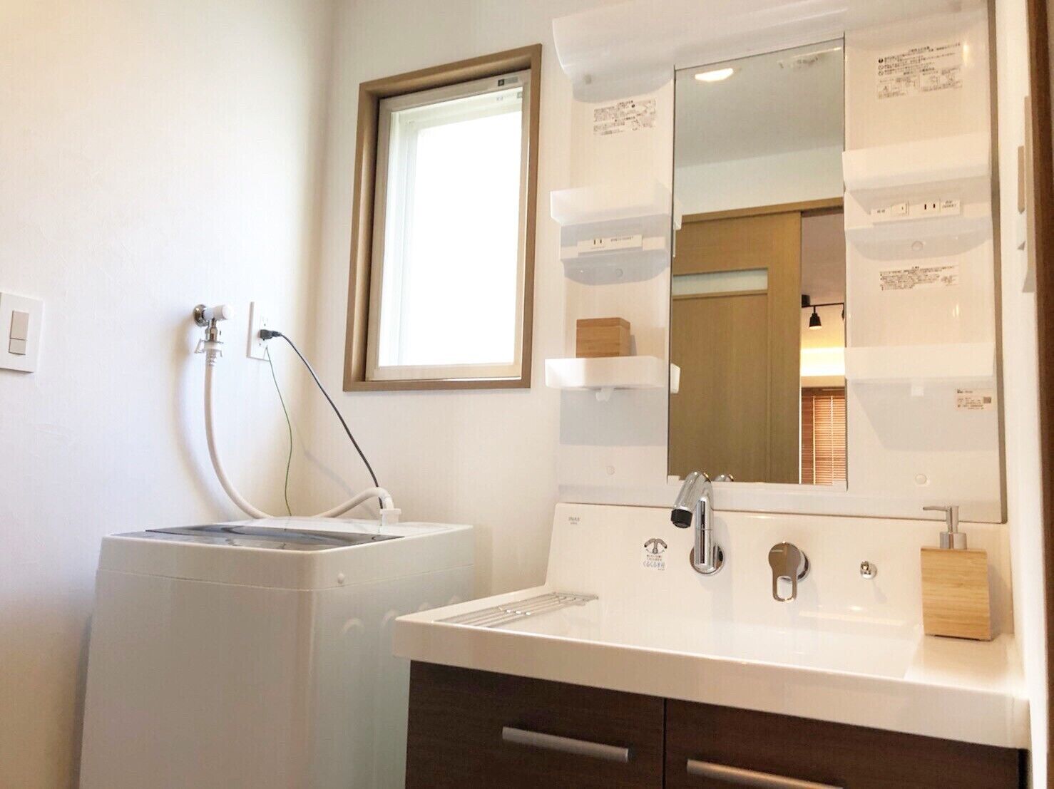 A modern bathroom with a white sink, a mirror, and a washing machine.