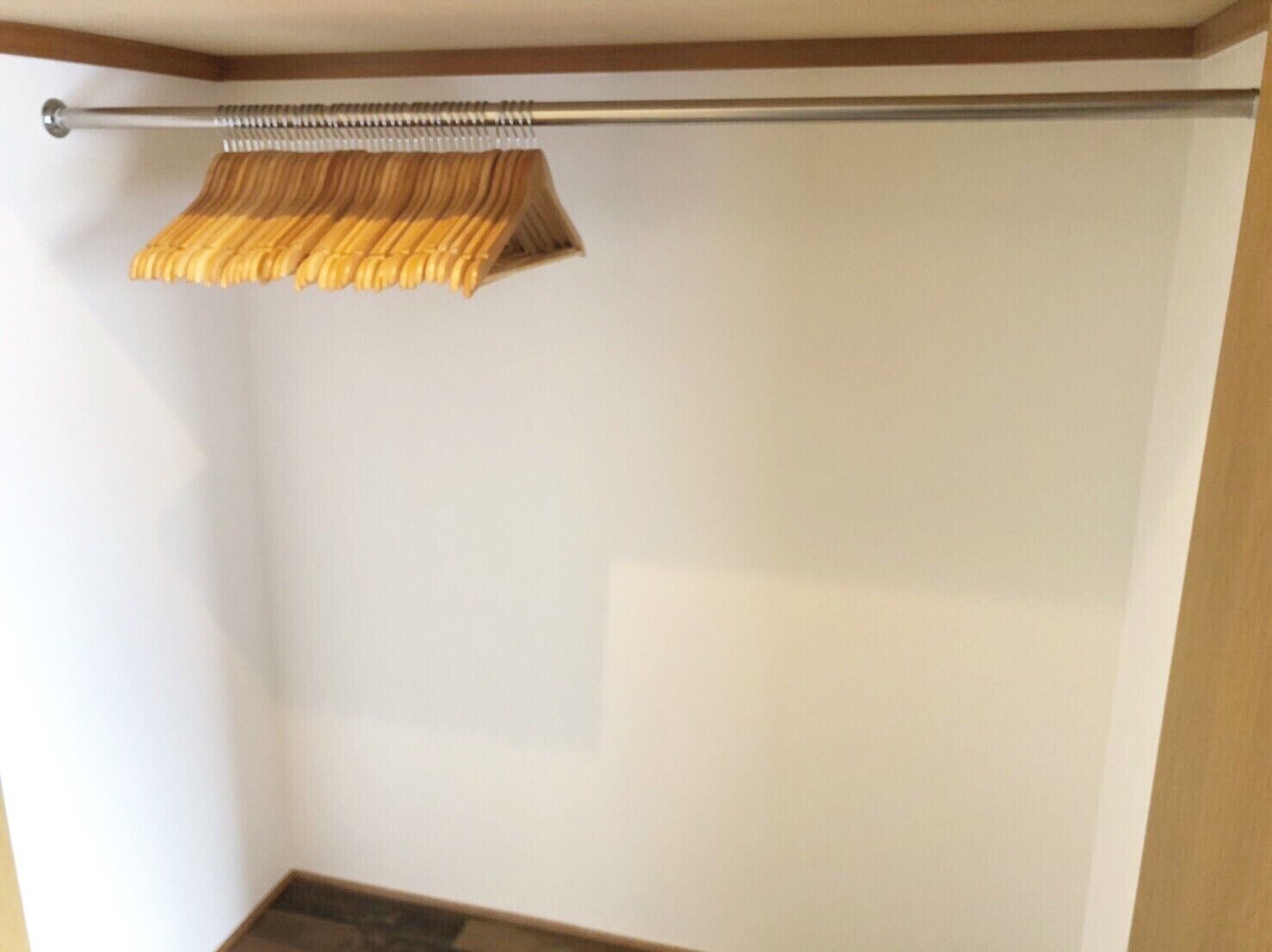 Un coin de pièce avec une tige métallique et un tissu tissé suspendu à celle-ci.
