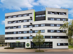 Un hôtel moderne, avec un hall d’accueil, de nombreux étages et un ciel dégagé.