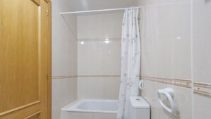 A small bathroom with a toilet, a shower with a curtain, and a wooden door. - 040 - Gran Playa 001 - Santa Pola (Santa Pola)