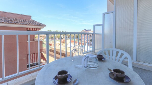 A balcony with a table set for two, a coffee pot, and a pitcher. - 040 - Gran Playa 001 - Santa Pola (Santa Pola)