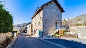 Una calle estrecha con edificios de piedra tradicionales, una escalera de madera y un cielo azul despejado.