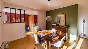 Un comedor con una mesa de madera, sillas, una lámpara colgante y un espejo sobre la mesa.