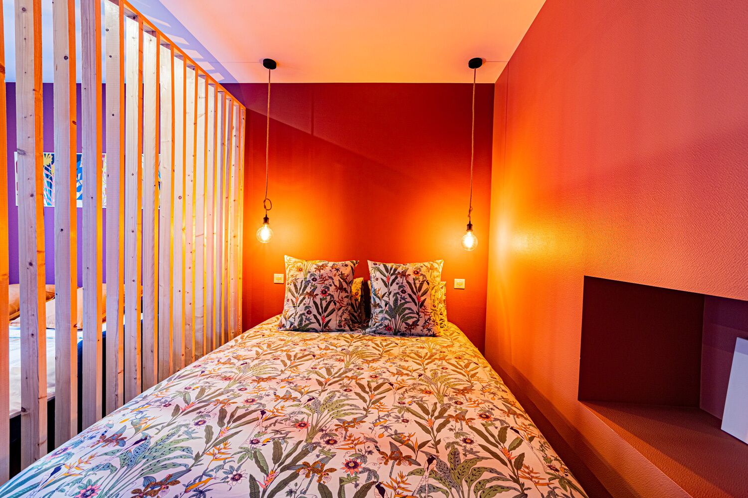 A bedroom with a bed, two pillows, and a wooden partition.
