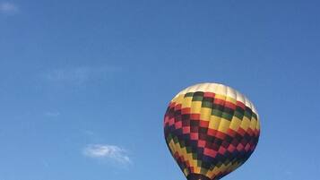 Een luchtballon met een kleurrijk geruit patroon tegen een helderblauwe lucht.