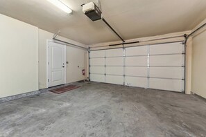Un garage avec un sol en béton, une porte blanche et une porte de garage.