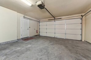Eine Garage mit Betonboden, einer weißen Tür und einem Garagentor.