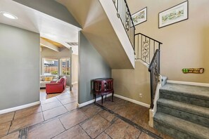 Ein geräumiger Wohnbereich mit einem roten Sofa, einem kleinen Holztisch und einer Treppe mit einer verzierten Geländer.