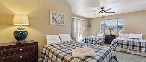 Une chambre d’hôtel avec deux lits, un ventilateur de plafond, un tableau et une lampe.