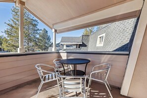 Ein überdachter Balkon mit rundem Tisch und vier Stühlen, mit Blick auf eine Wohngegend mit Häusern und Bäumen.