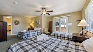 A hotel room with two beds, a ceiling fan, a window with blinds, a lamp, and a door leading to a balcony. - Spacious Tahoe Retreat with Rooftop Deck & Mountain Views (South Lake Tahoe)