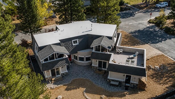 A modern two-story house with a covered patio, a driveway, and a small garden area. - Spacious Tahoe Retreat with Rooftop Deck & Mountain Views (South Lake Tahoe)