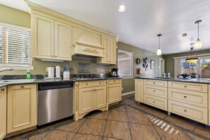 Una cocina amplia con armarios color beige, un lavavajillas de acero inoxidable y una isla grande con fregadero.