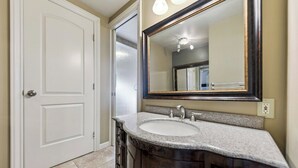 A bathroom with a white door, a vanity with a sink, and a large mirror. - Spacious Tahoe Retreat with Rooftop Deck & Mountain Views (South Lake Tahoe)