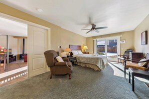 Ein Hotelzimmer mit Bett, Stuhl, Schreibtisch, Lampe und Deckenventilator.