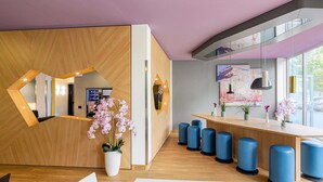 A modern reception area with a wooden reception desk, blue stools, and potted orchids.