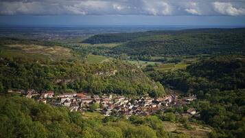Ein Dorf eingebettet in ein Tal, umgeben von grünen Hügeln und Häusern.