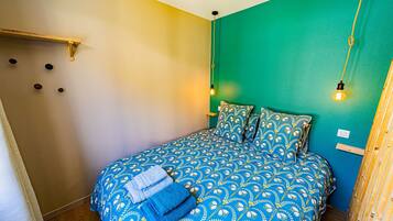 Un lit avec une couvre-lit et des oreillers à motifs bleus, une tête de lit en bois et deux appliques murales.