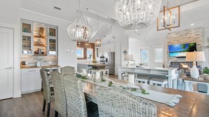 Une cuisine spacieuse dotée d’appareils électroménagers modernes, un coin repas avec des chaises en osier et un grand lustre.