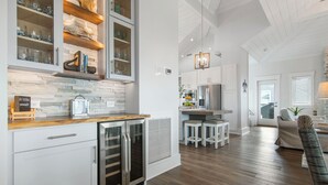 Une cuisine moderne avec des meubles blancs, un pare-feu en pierre et un plan de travail en bois.