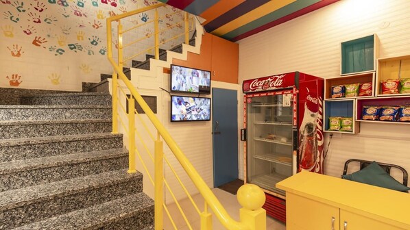 Una escalera con barandales amarillos, un refrigerador Coca-Cola y decoraciones de huellas en la pared.