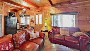 Ein Ferienhäuschen mit Holzausstattung, einem Essbereich und einem Wohnzimmer mit Ledersofas.
