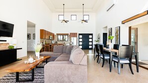 Un espacio habitable amplio con un sofá modular grande, una mesa de centro de madera y un comedor con una mesa y sillas de madera oscura.