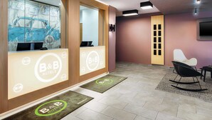 Een hotel receptie met een modern design, inclusief een receptiebalie, een groot raam met een auto ontwerp en een zithoek met een schommelstoel.
