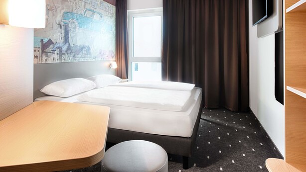 Een hotelkamer met twee bedden, een bureau, een stoel, een televisie en een kaart aan de muur.