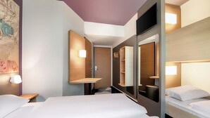 Een moderne hotelkamer met een groot bed, nachtkastje, spiegel en ingebouwde planken.