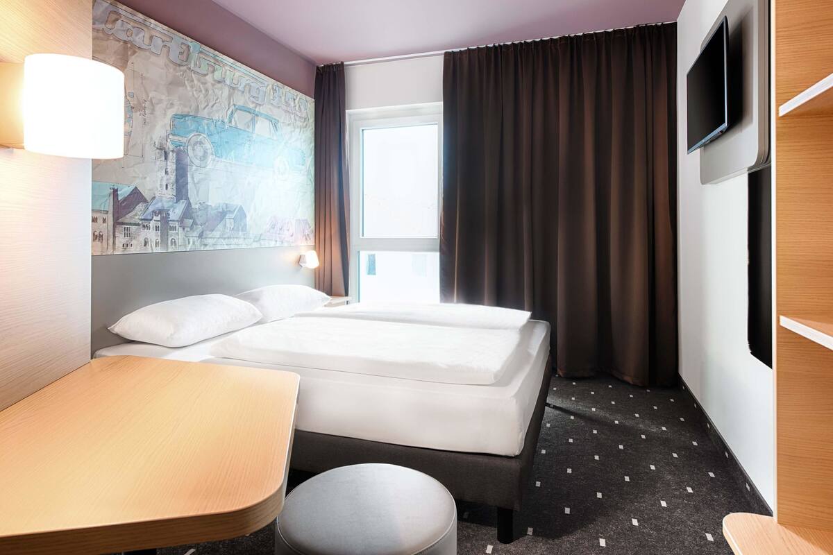 Une chambre d’hôtel avec deux lits, un bureau, une chaise, une télévision et une carte accrochée au mur.