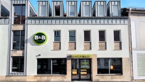 Een bed en breakfast hotel met een receptie, meerdere ramen en een groen logo.