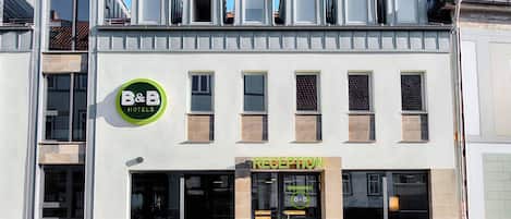 Un hotel tipo bed and breakfast con una recepción, varias ventanas y un logotipo verde.