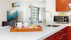 Una cocina moderna con encimera de mármol, pileta de acero inoxidable, microondas y muebles de madera.