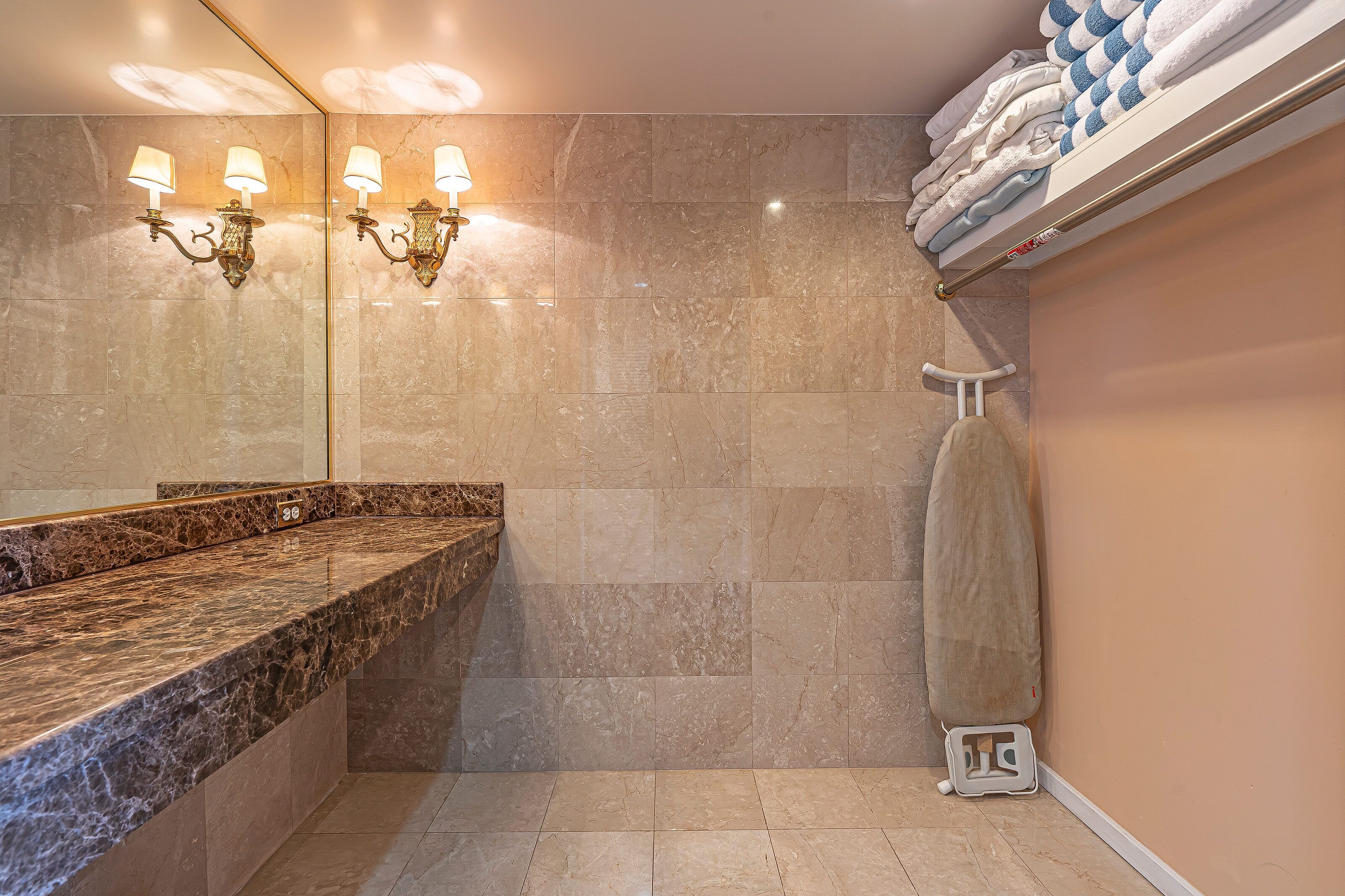 A bathroom with a marble countertop, a towel rack, and a mirror.