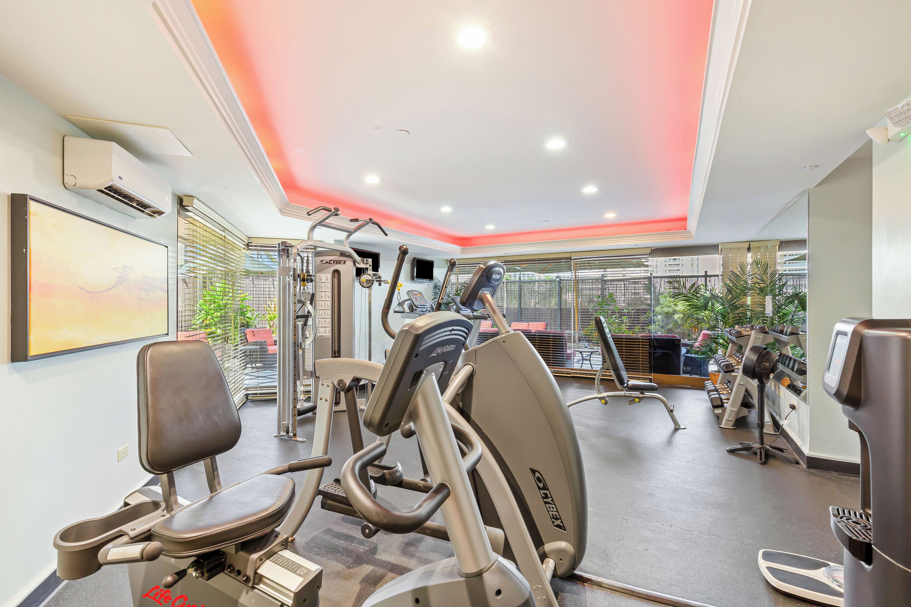 Un gimnasio con máquinas de cardio, máquinas de pesas y un espejo grande.