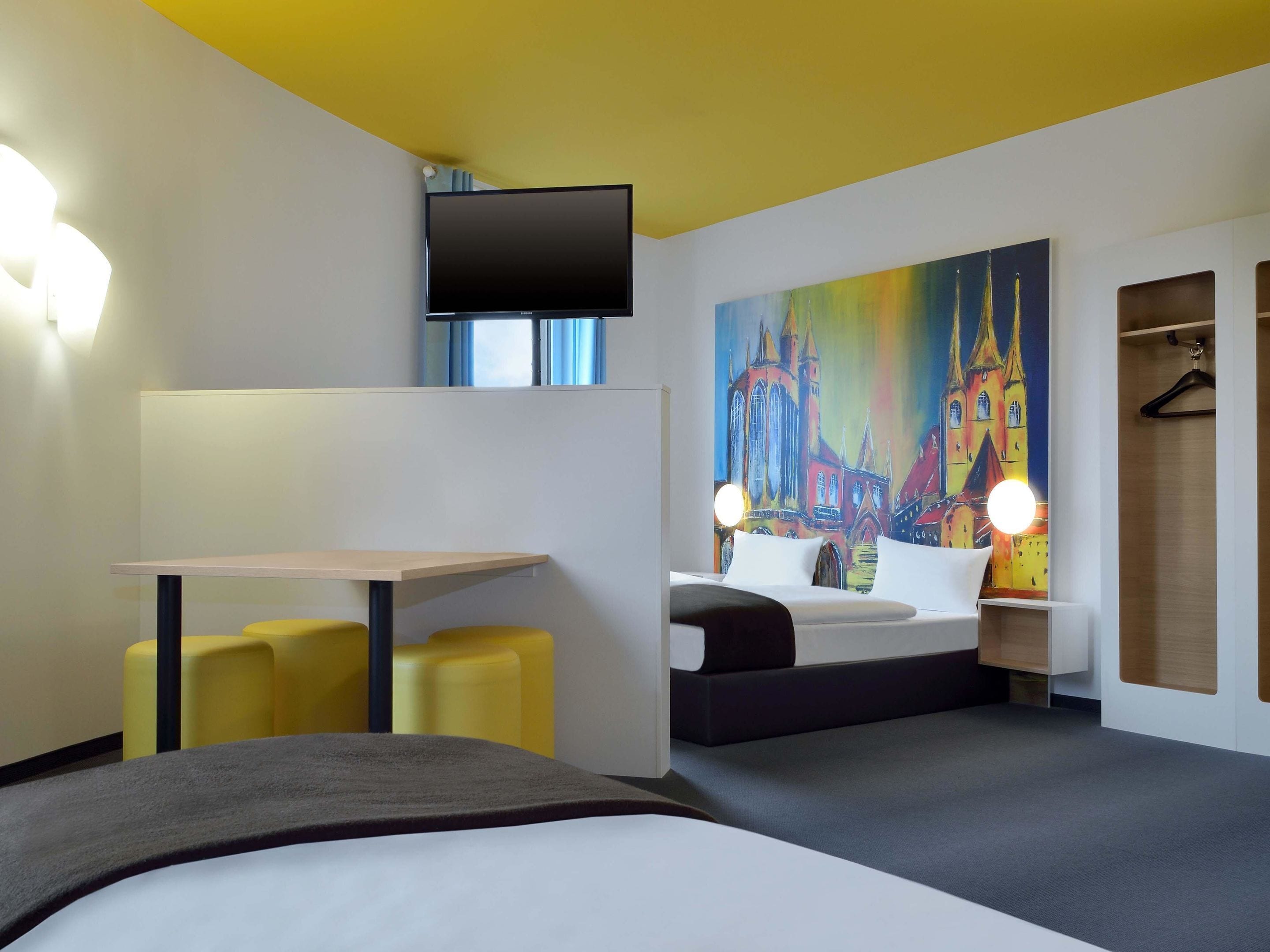 Una habitación de hotel moderna con una cama, un escritorio y una pintura de una catedral.