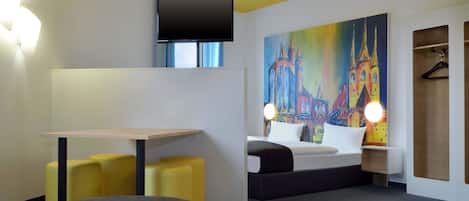Una habitación de hotel moderna con una cama, un escritorio y una pintura de una catedral.