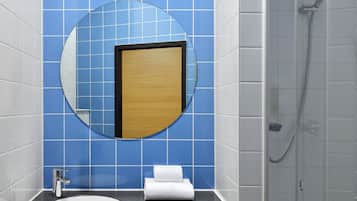 Ein Badezimmer mit rundem Spiegel, Waschbecken, Handtuch und Dusche.