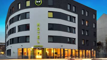 Un hotel moderno con una fachada curva, una zona de recepción y el letrero visible de la cadena B&B Hotels.