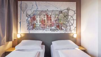 A hotel room with two single beds, a large wall map, and a nightstand with a lamp.