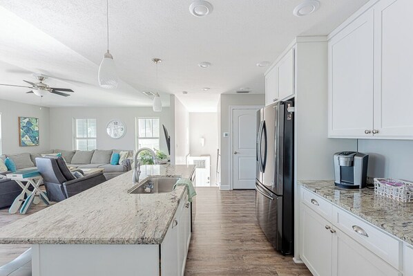 A modern kitchen with white cabinets, a granite countertop, and stainless steel appliances.