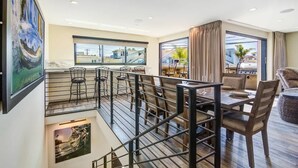 A dining area with a view of the city, a balcony with a railing, and a dining table with chairs.