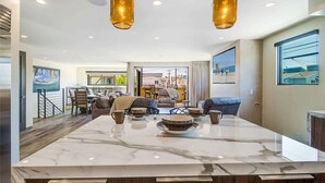 A spacious living area with a marble island, modern furniture, and pendant lighting.