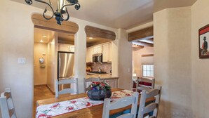 A dining area with a wooden table, white chairs, and a chandelier. - Comfortable Family Home, Walk to The Plaza (Santa Fe)