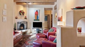 A cozy living room with a fireplace, leather sofas, a patterned rug, and a painting of a woman. - Comfortable Family Home, Walk to The Plaza (Santa Fe)