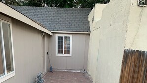 A backyard with a paved area, a window, and a wooden fence. - Lovelock Pet-Friendly Studio Next to I-80 (Lovelock)